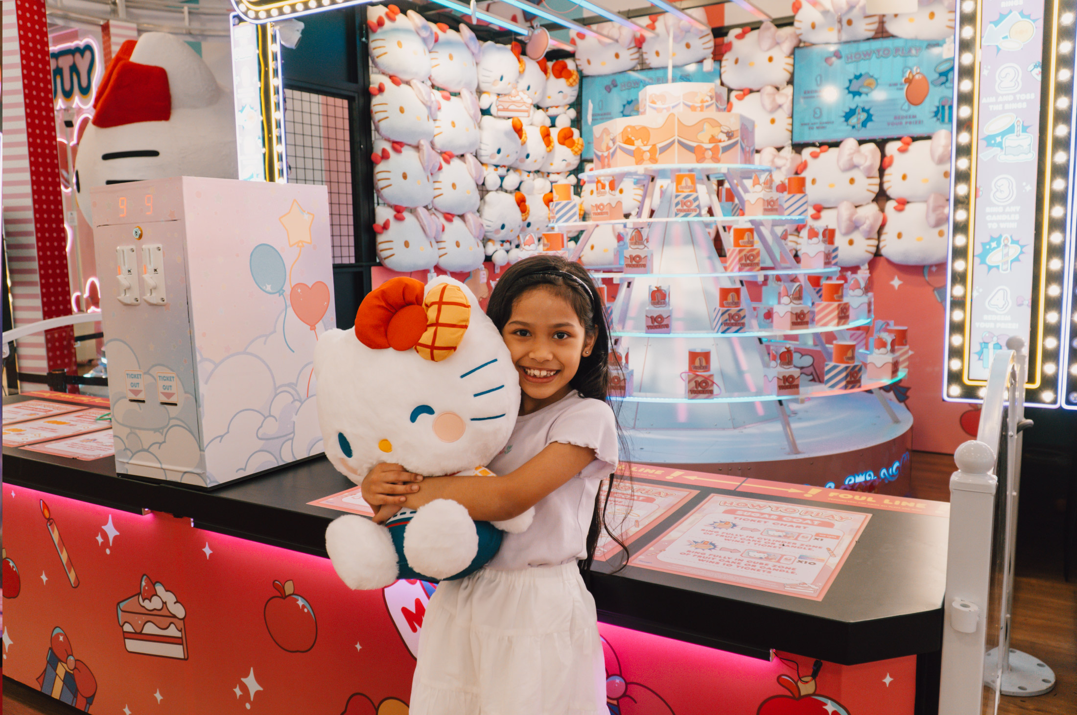 Child holding up her Hello Kitty carnival game prize at Changi Airport 